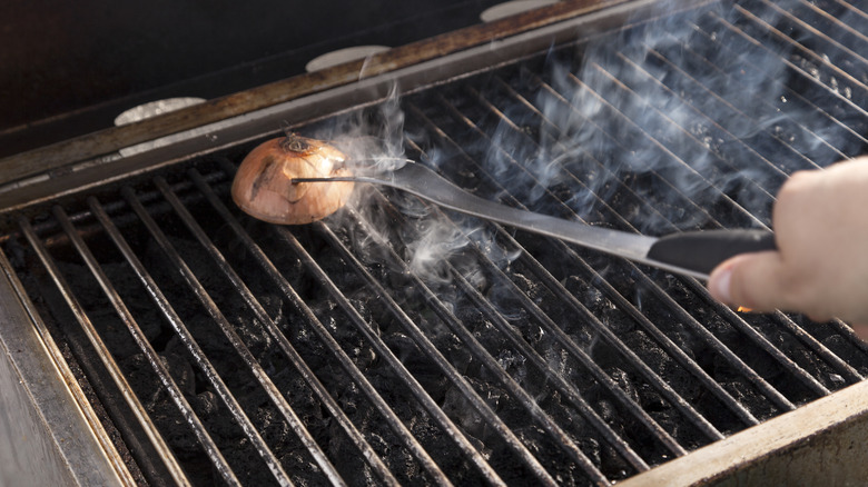 A man cleaning his grill with an onion