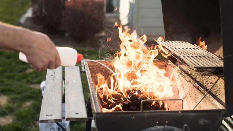 A man using lighter fluid on his grill