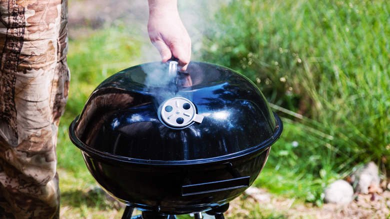 Man lifting the cover on his grill