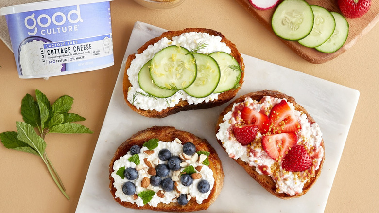 Good Culture cottage cheese container next to slices of bread with cottage cheese and fruit