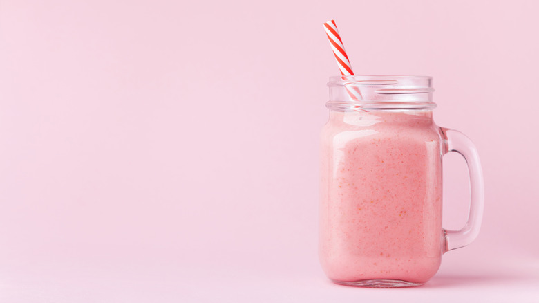 Pink smoothie in glass cup with straw