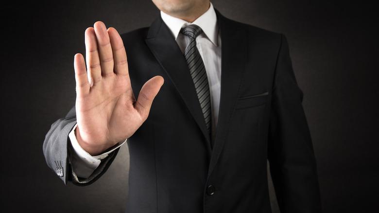 Man holding hand up to block entry