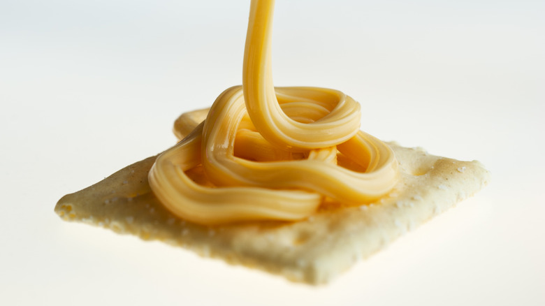 Cheese pouring onto cracker