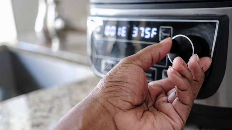 Hand adjusting the settings on an air fryer