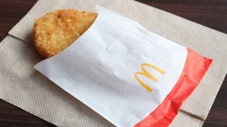 A McDonald's hash brown rests in a paper sleeve.