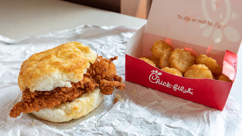 A Chick-fil-A breakfast sandwich is shown with some hash brown bites.