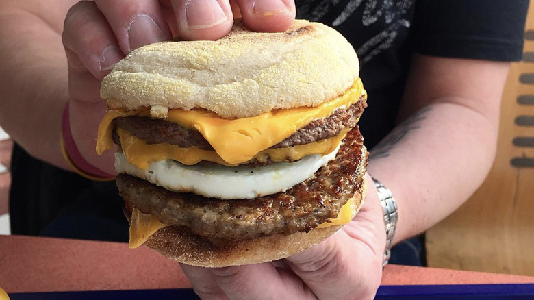 A person holds a Mc10:35 breakfast sandwich.