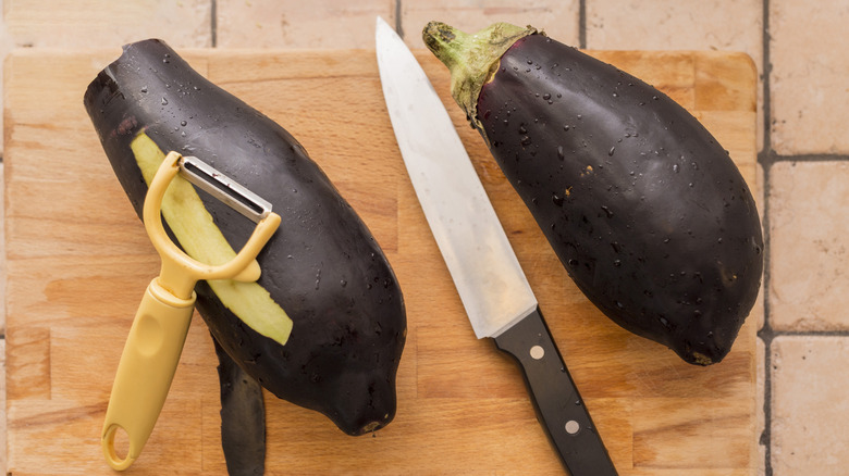 slightly peeled eggplant with peeler and knife