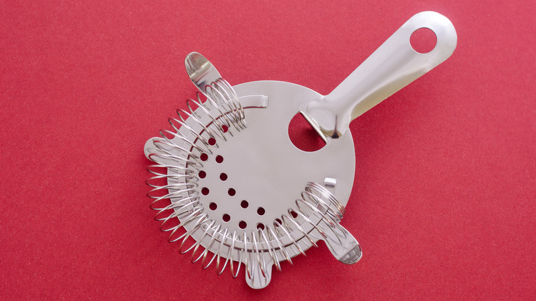 cocktail strainer on red background