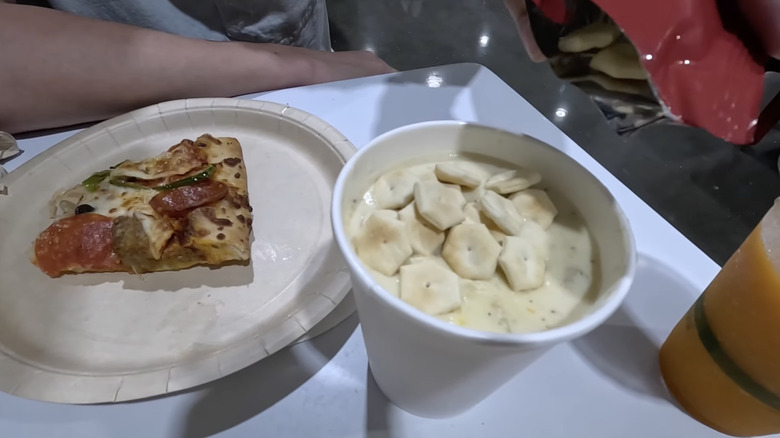 Japan Costco's container of clam chowder with oyster crackers on top next to plate of half-eaten pizza