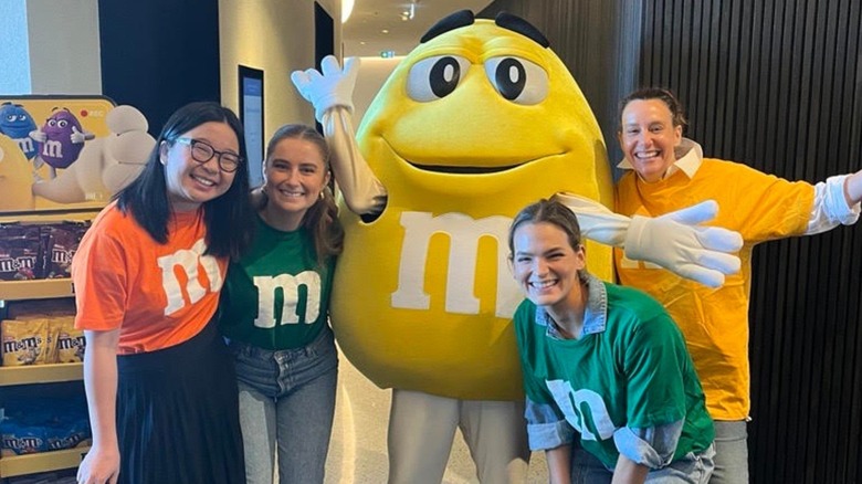 Several people posing with the yellow M&M's mascot