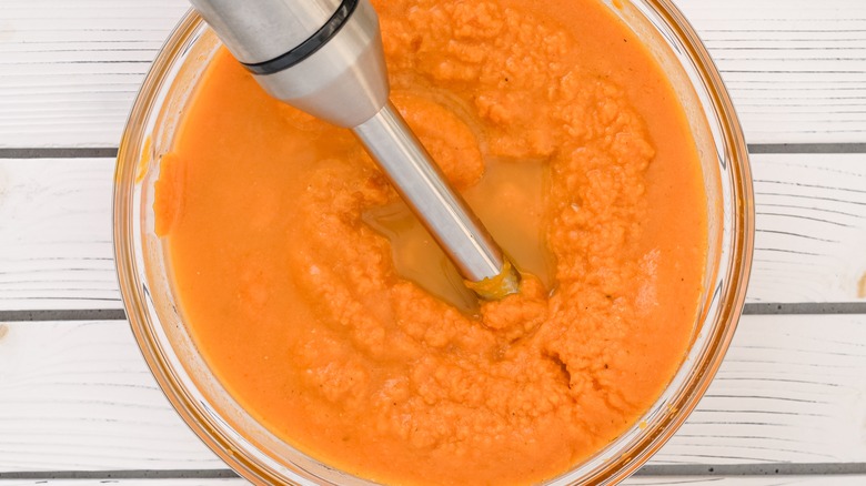 Close-up of a hand blender mixing pumpkin puree