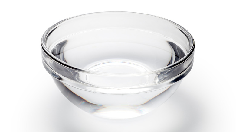 Glass bowl with water on white background 