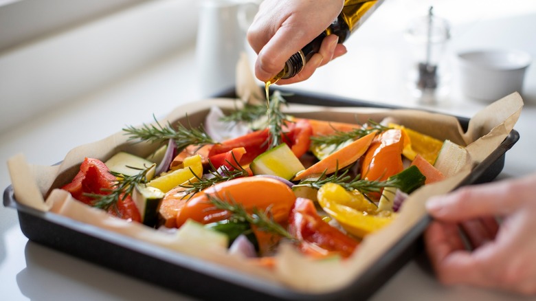 Hand drizzling oil on vegetables