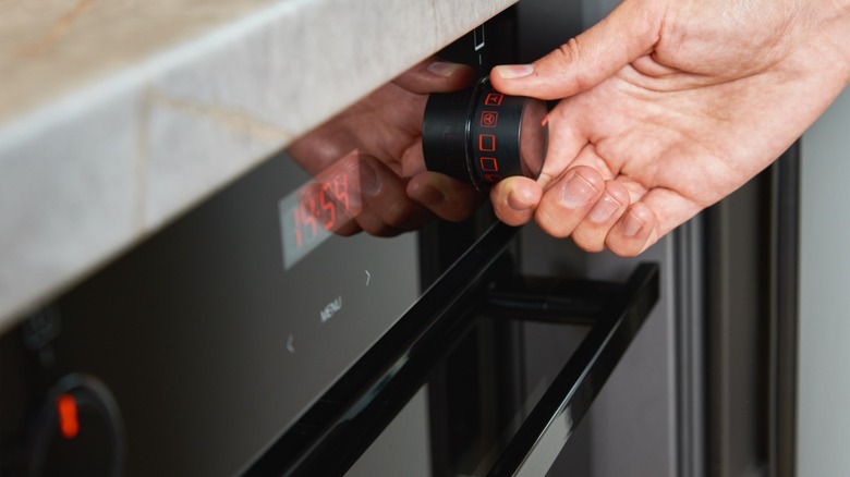 A hand turning on oven