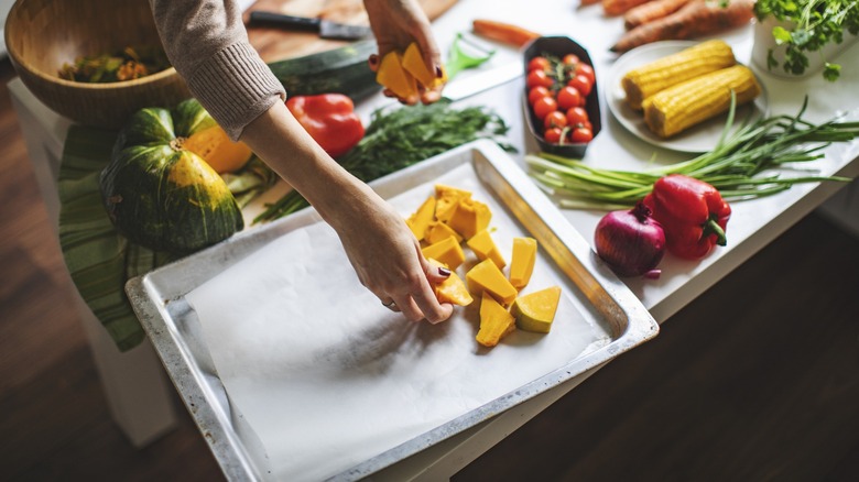 Hand putting vegetables on sheet pan