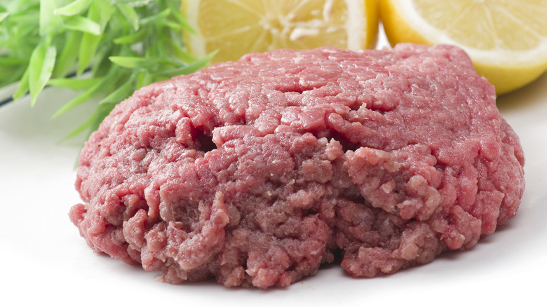 ground horse meat patty with lemon in the background