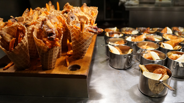 Savory ice cream cones on a stand and mini pots of food next to them