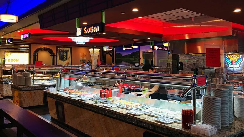 Person working behind a sushi bar at a buffet restaurant