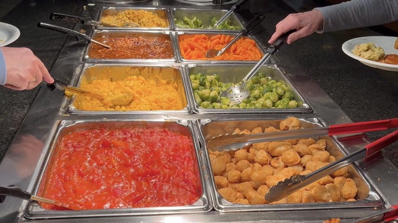 Hands scooping food from a buffet station