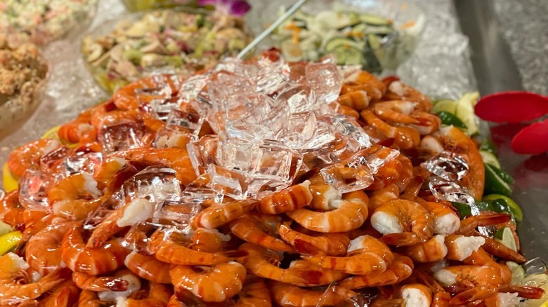 A mountain of shrimp with ice on top at a buffet