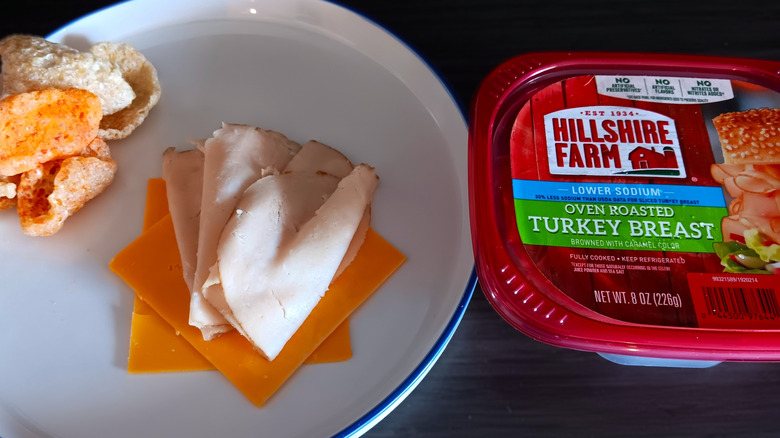 Hillshire Farm deli turkey in package and on plate with slices of cheese and pork rinds