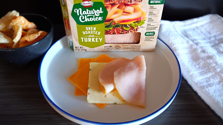 Hormel Natural Choice deli turkey package with slices on plate alongside slices of cheese