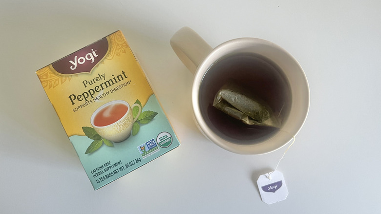 Box of yogi purely peppermint tea next to cup of tea