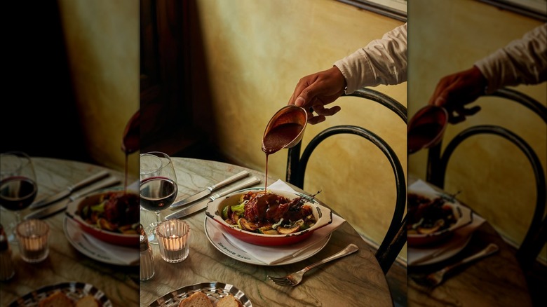 Waiter pouring sauce over a dish at Cafe Boheme London