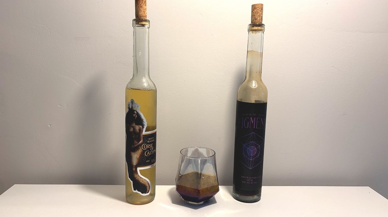 Two bottles and one glass of Batch mead on a white table