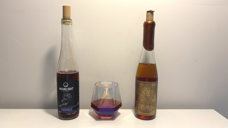 Two bottles and one glass of Moonlight mead on a white table