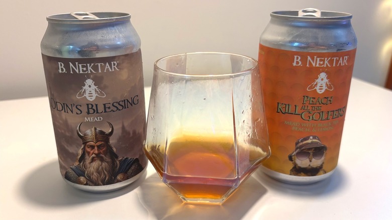 Two cans and one glass of B. Nektar mead on a white table