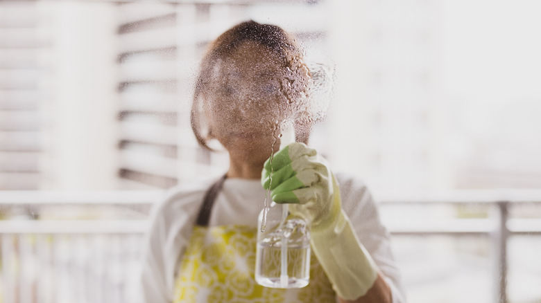 Person spraying a window with a water solution