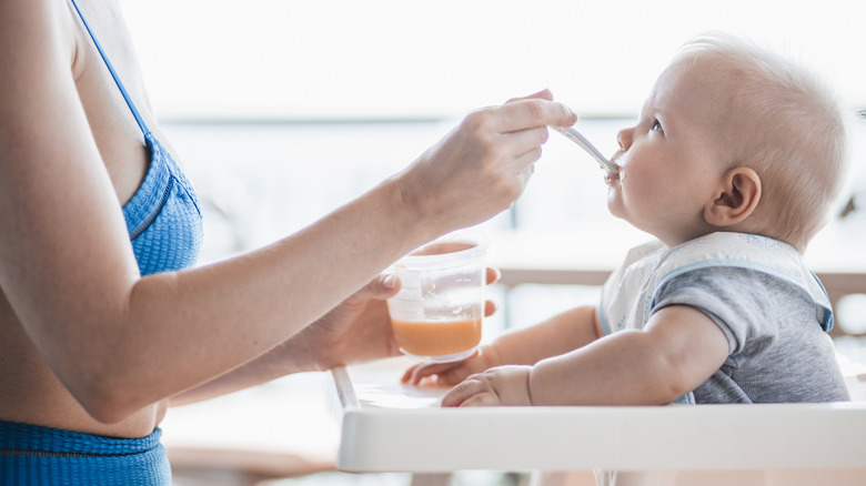 Person feeding a baby from a tub