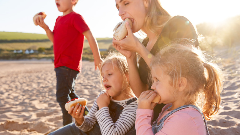 family eating hot dogs beach