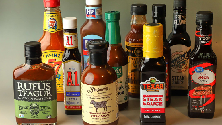 Various bottles of steak sauces are grouped on a table.