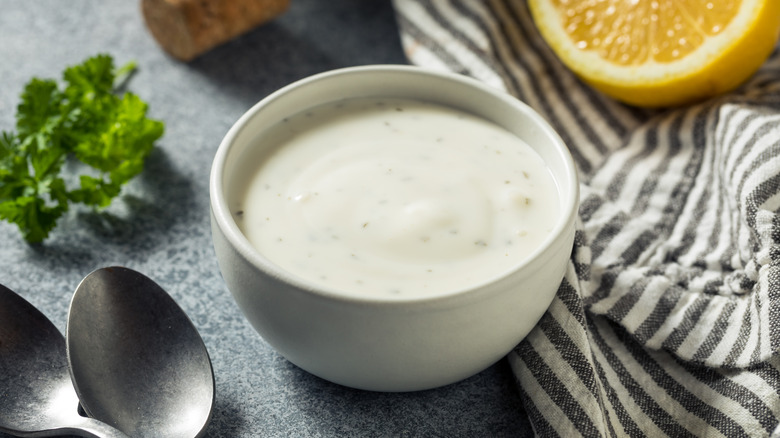 Ranch dressing in white bowl next to parsley and lemon