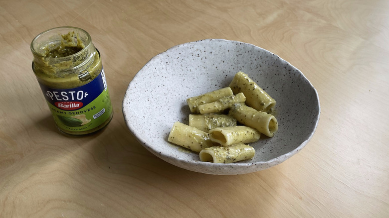 jarred pesto next to pasta bowl 