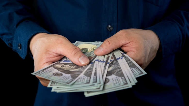 man holding $100 dollar bills