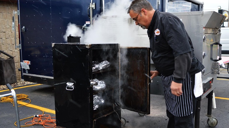 chef smoking meat in a box smoker for competition