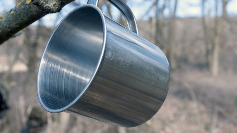 Stainless steel mug hanging off a tree branch