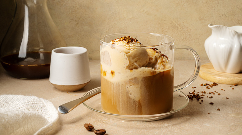 Affogato in a clear glass mug surrounded by pottery