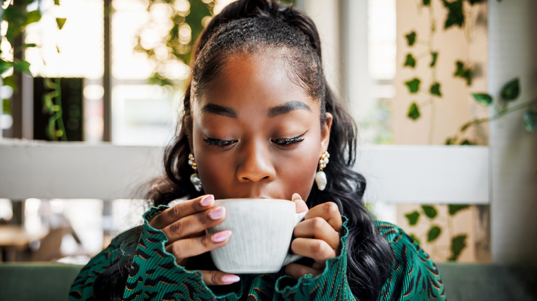 Woman sipping out of white mug