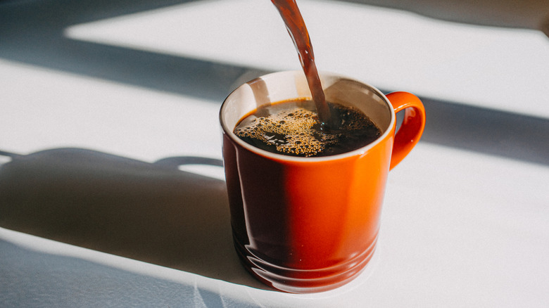 Coffee being poured into bright orange mug