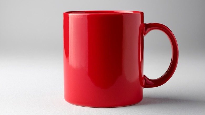 Red mug with handle against grey background
