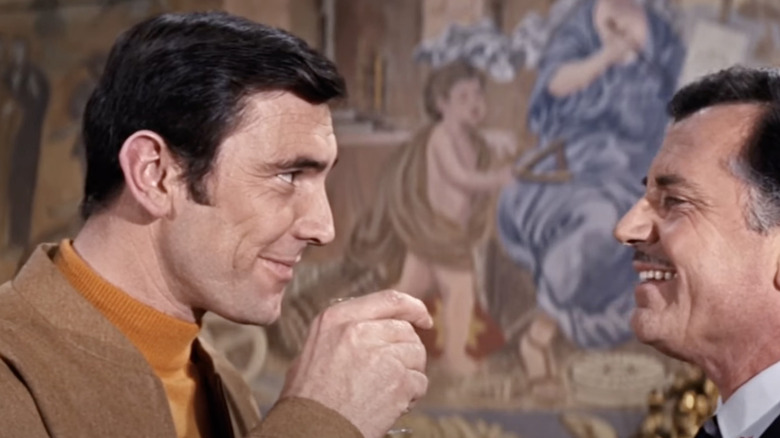 George Lazenby in a scene of On Her Majesty's Secret Service drinking bourbon