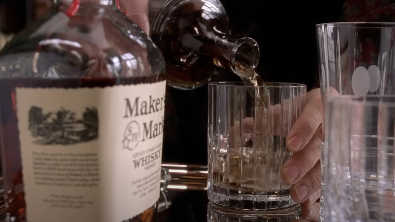 A bottle of Maker's Mark bourbon and a glass being poured