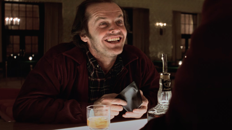 Jack Nicholson smiling at a bar drinking Jack Daniels in the movie The Shining