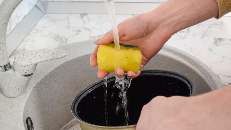 Woman washing pot in sink