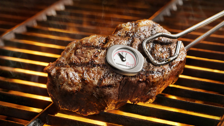 Grilling steak with meat thermometer